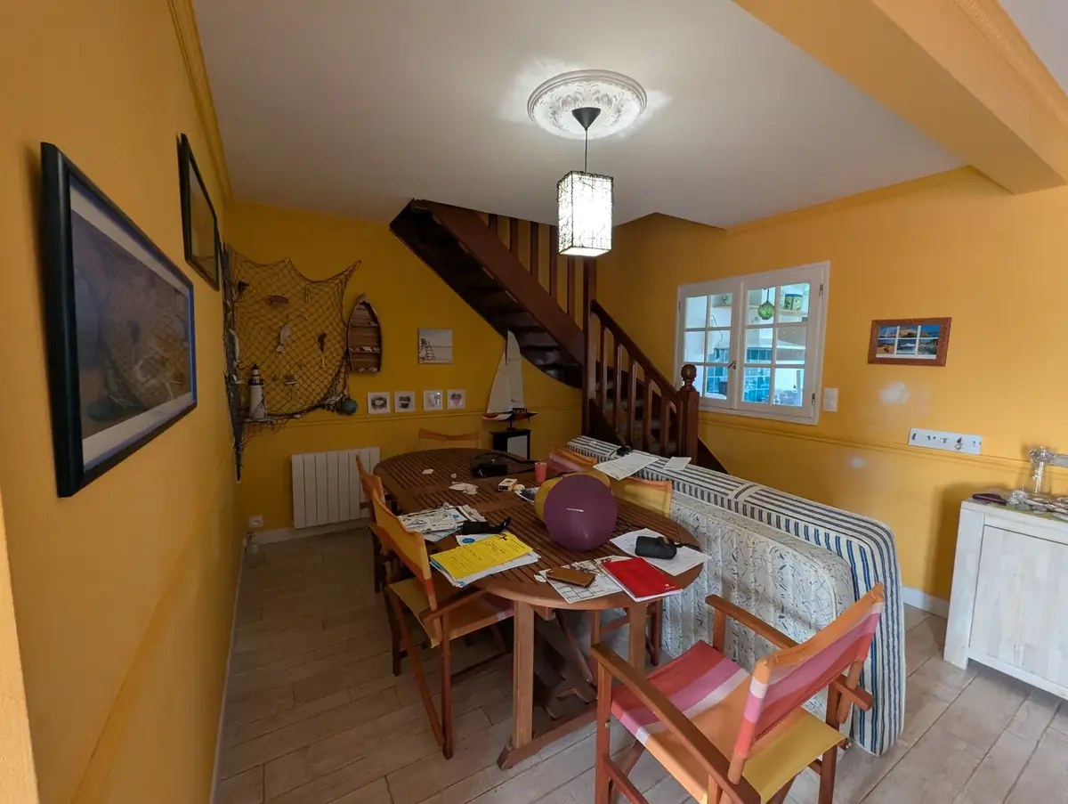 Pièce de vie d’une maison de bourg de Belz avant travaux, murs jaunes du sol au plafond et escalier en bois verni