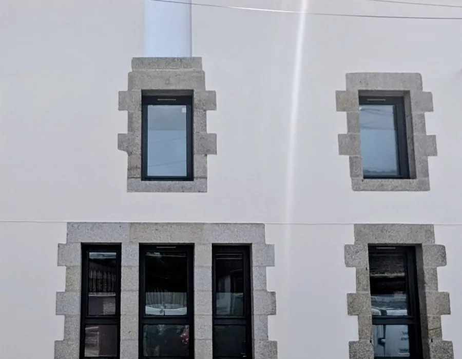 Encadrements de granit laissés apparents sur la façade ravalée d’un immeuble de bourg à Sarzeau