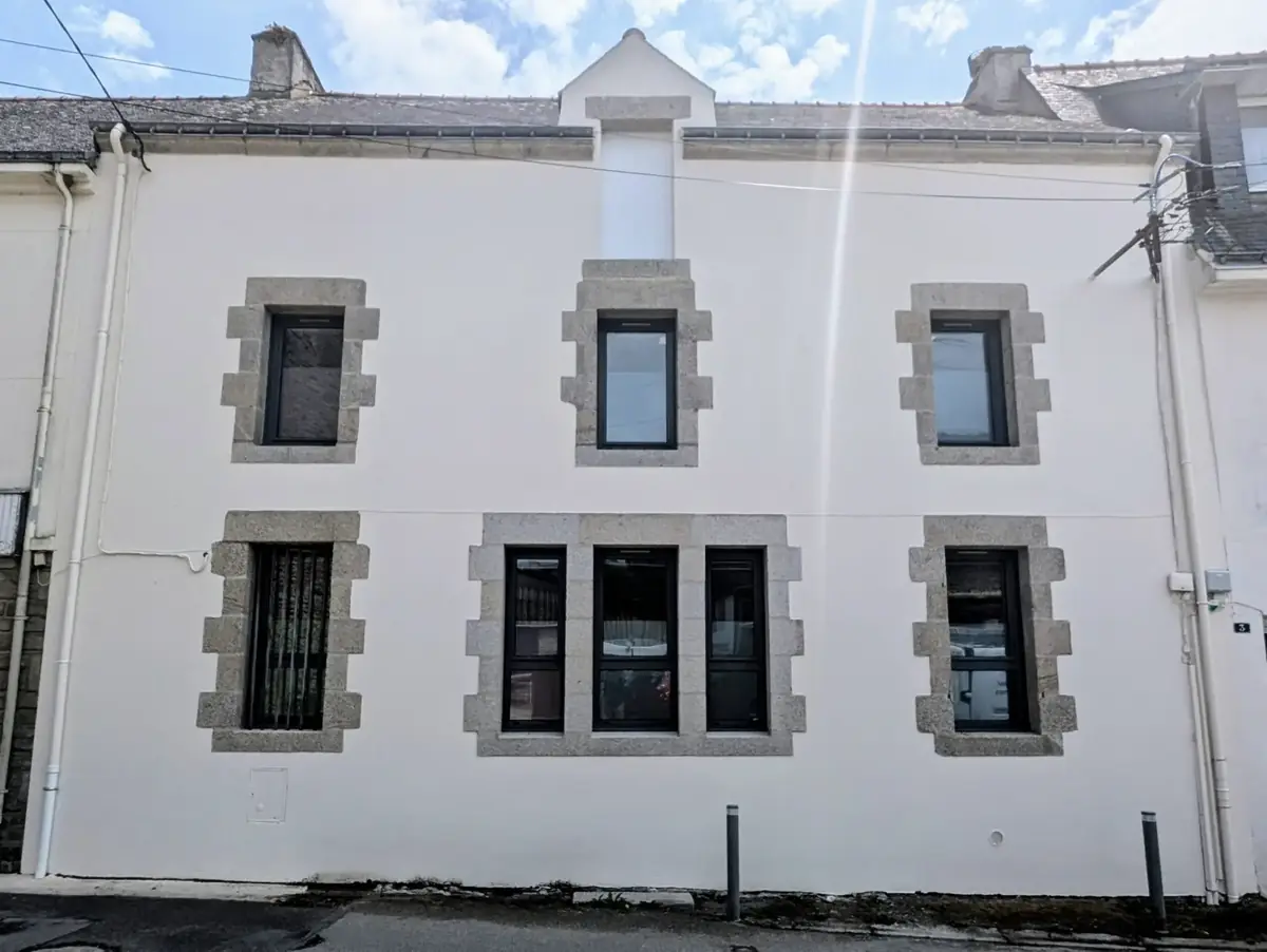 Immeuble de bourg à Sarzeau après ravalement, vu de trois quarts, enduit clair et encadrements de granit apparents