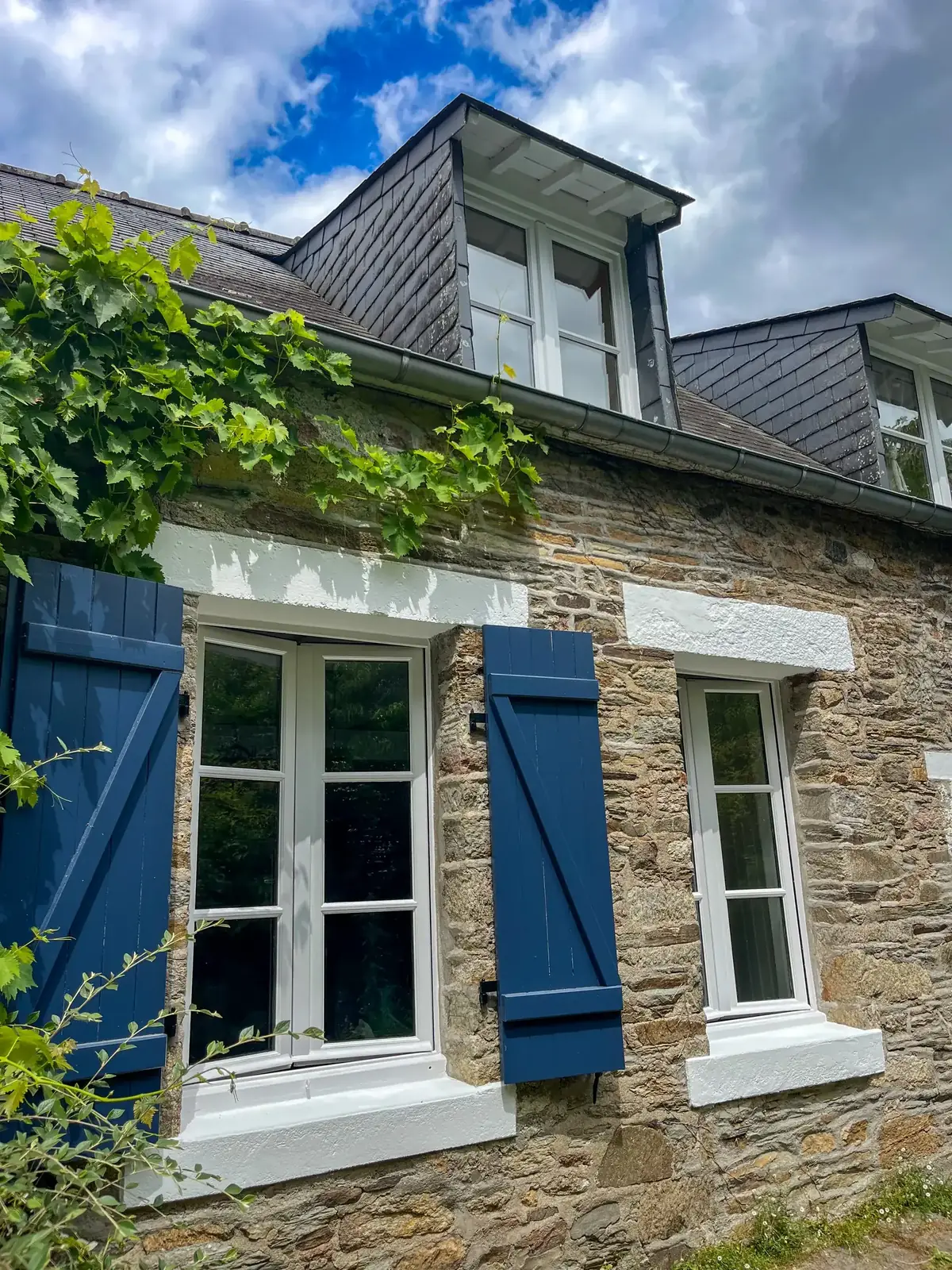 Fenêtres et volets d’une longère de Peillac après mise en teinte, mur en moellon laissé nu sous la vigne