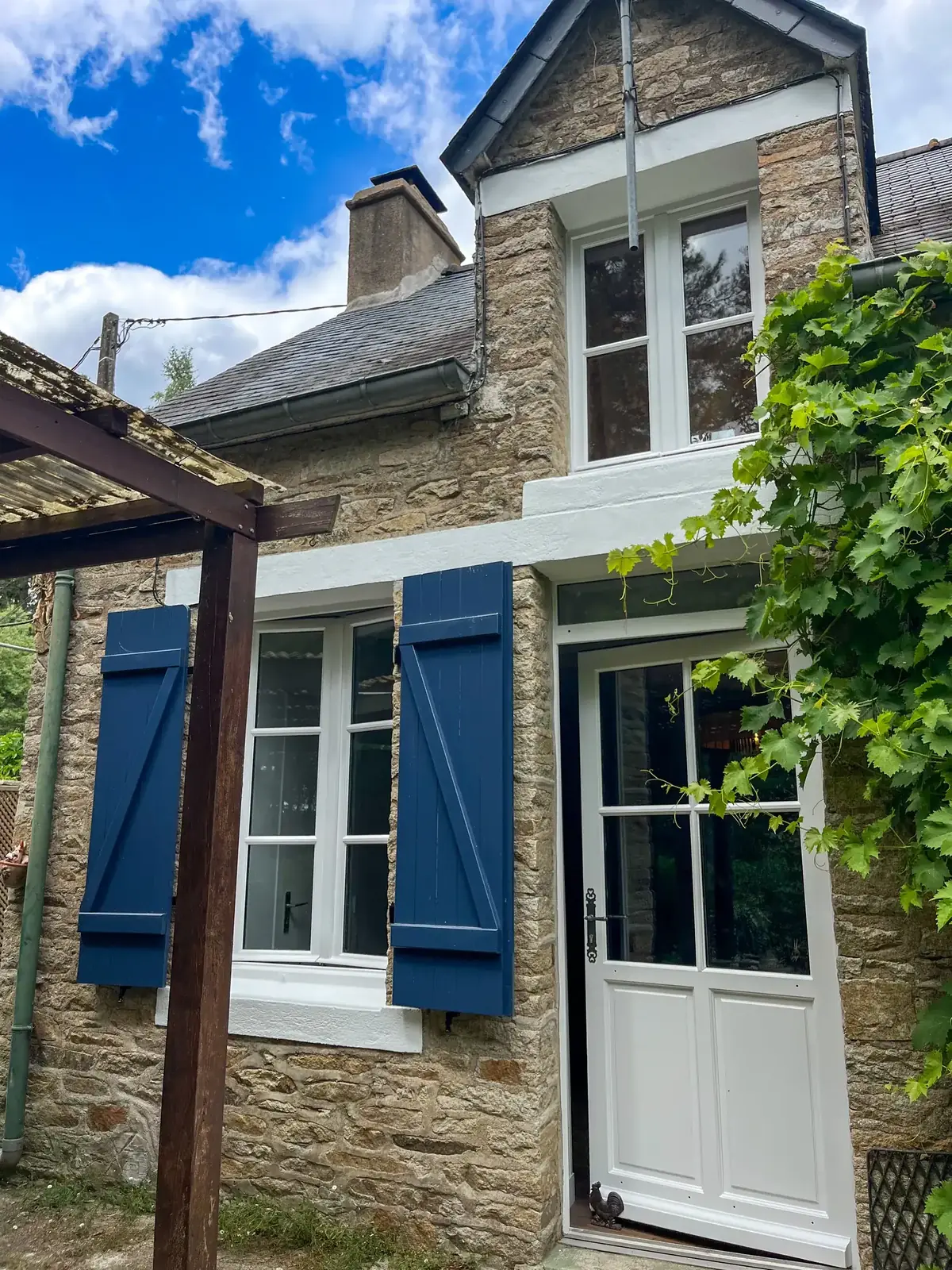 Porte d’entrée et fenêtre reprises en blanc sur une longère de Peillac, volets bleus et linteau clair