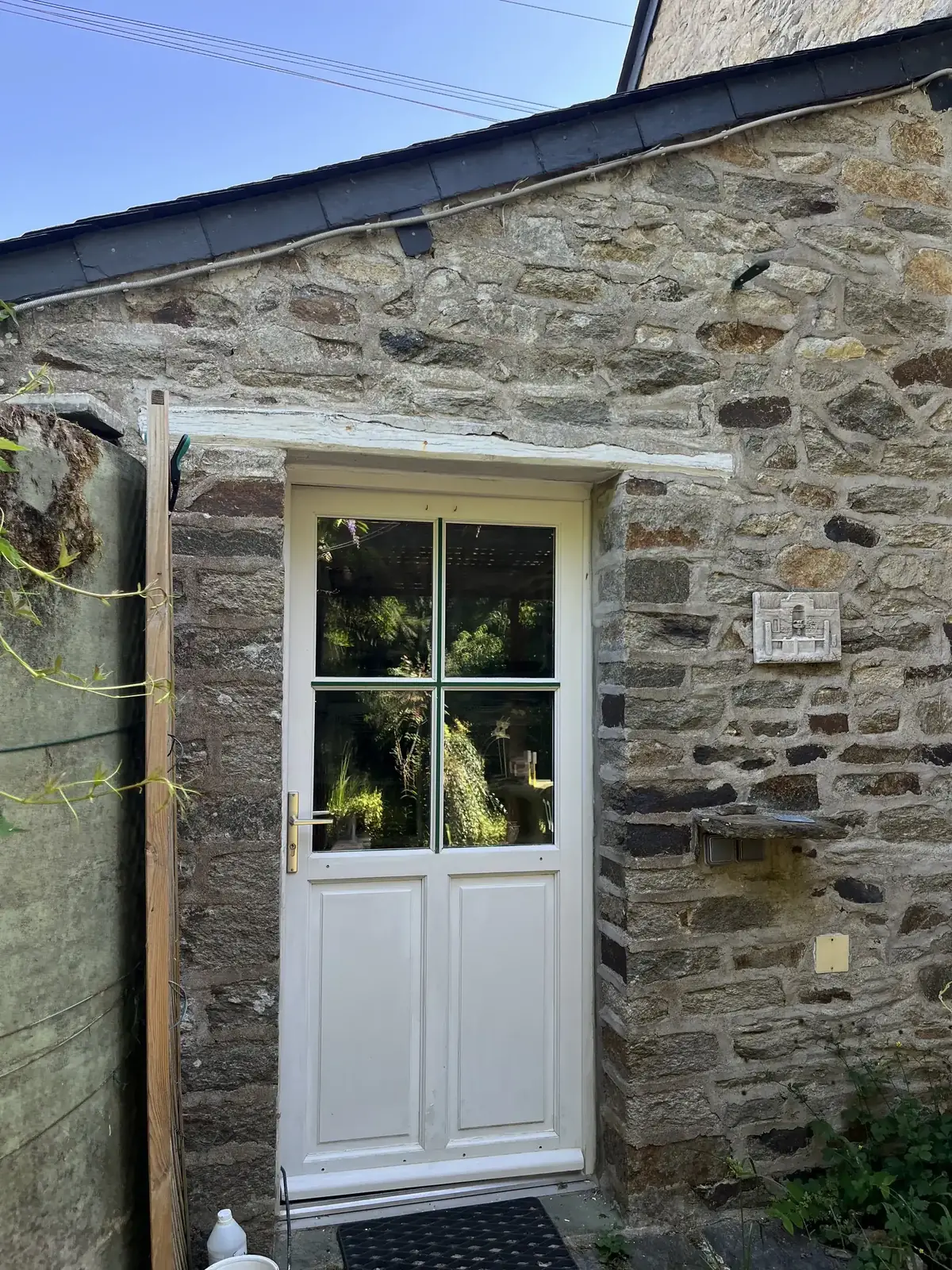 Porte vitrée d’une dépendance en pierre à Peillac, encadrement bois et mur de moellon, pendant le chantier