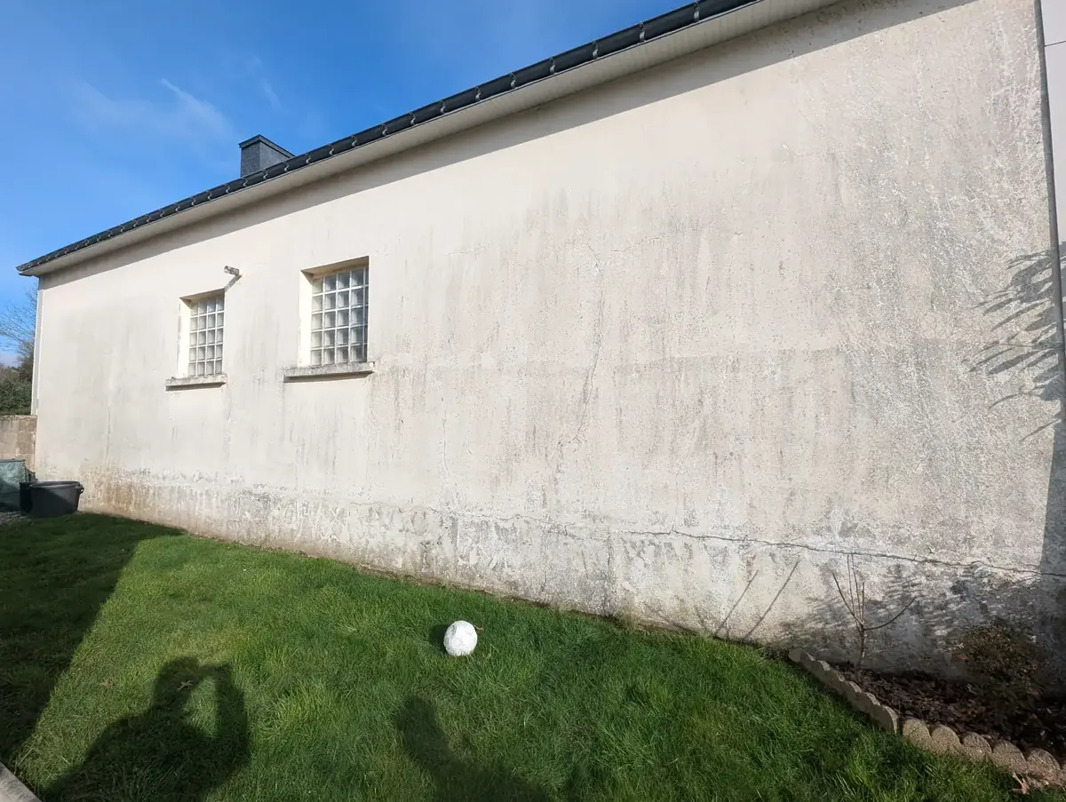 Mur enduit d’une longère de Pleucadeuc avant ravalement, fissure horizontale et pied de mur encrassé