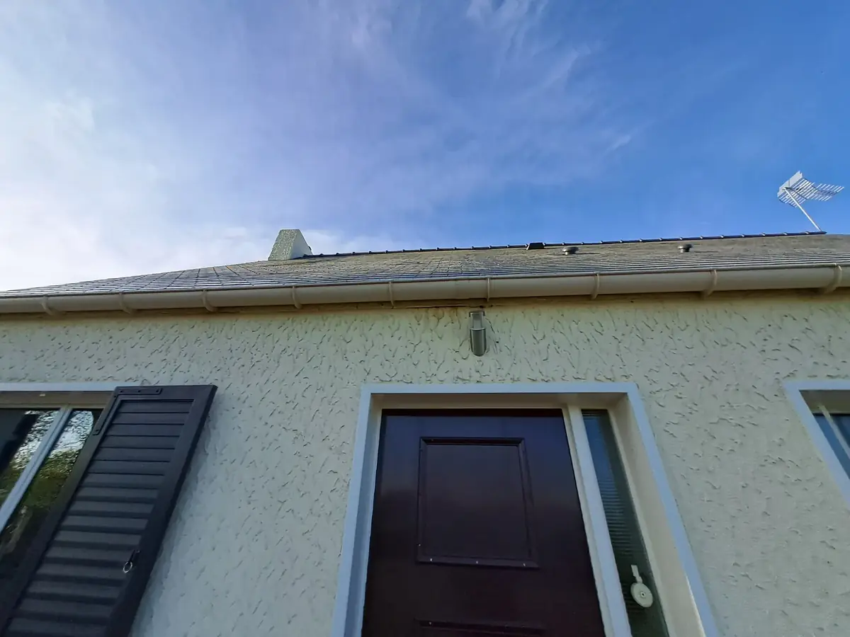 Haut de façade d’une maison de Pleucadeuc, débord de toit, gouttière et porte d’entrée en ton soutenu