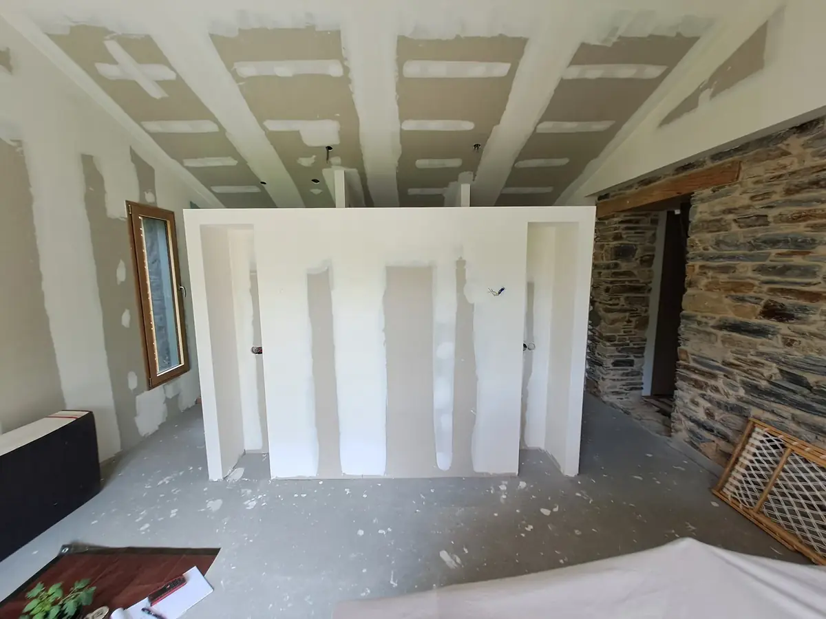 Pièce de vie à Saint-Congard, cloison neuve en plaque de plâtre enduite, plafond en rampant et mur de schiste laissé brut à droite