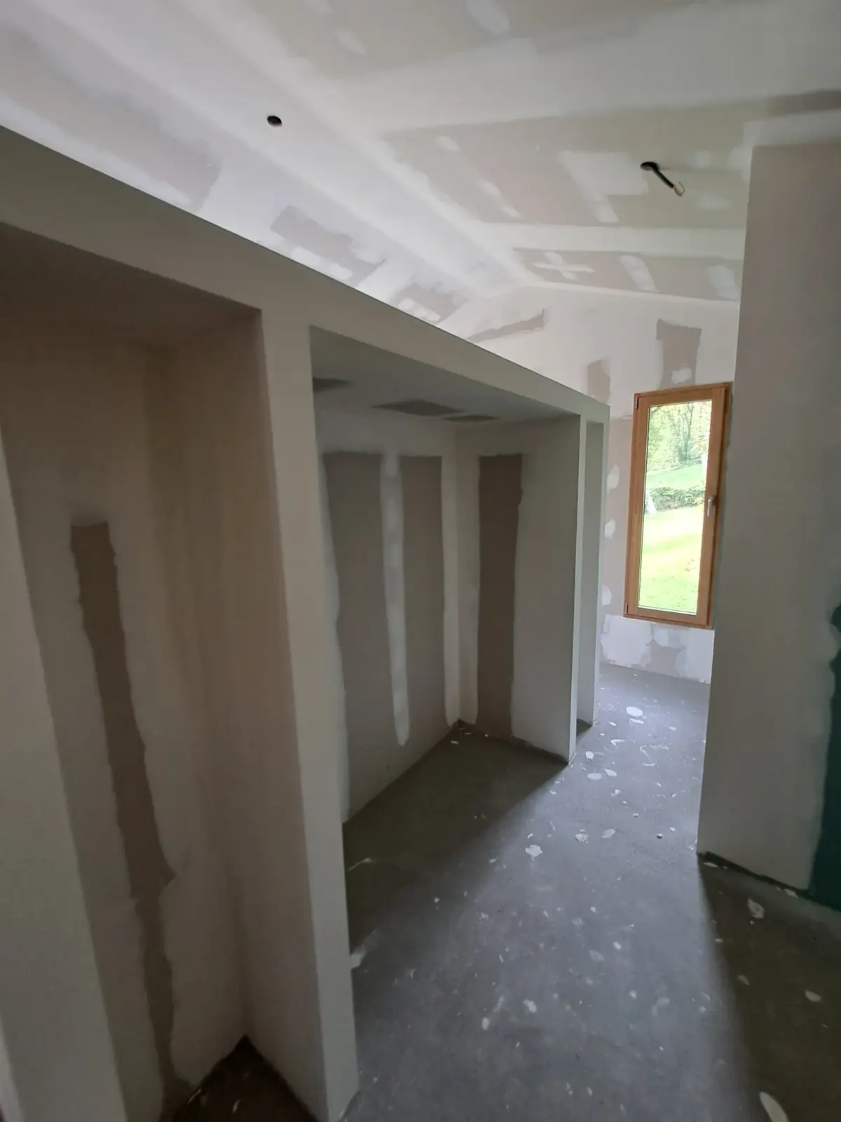 Cloisons et retombées en plaques de plâtre à Saint-Congard, fenêtre bois en fond de pièce