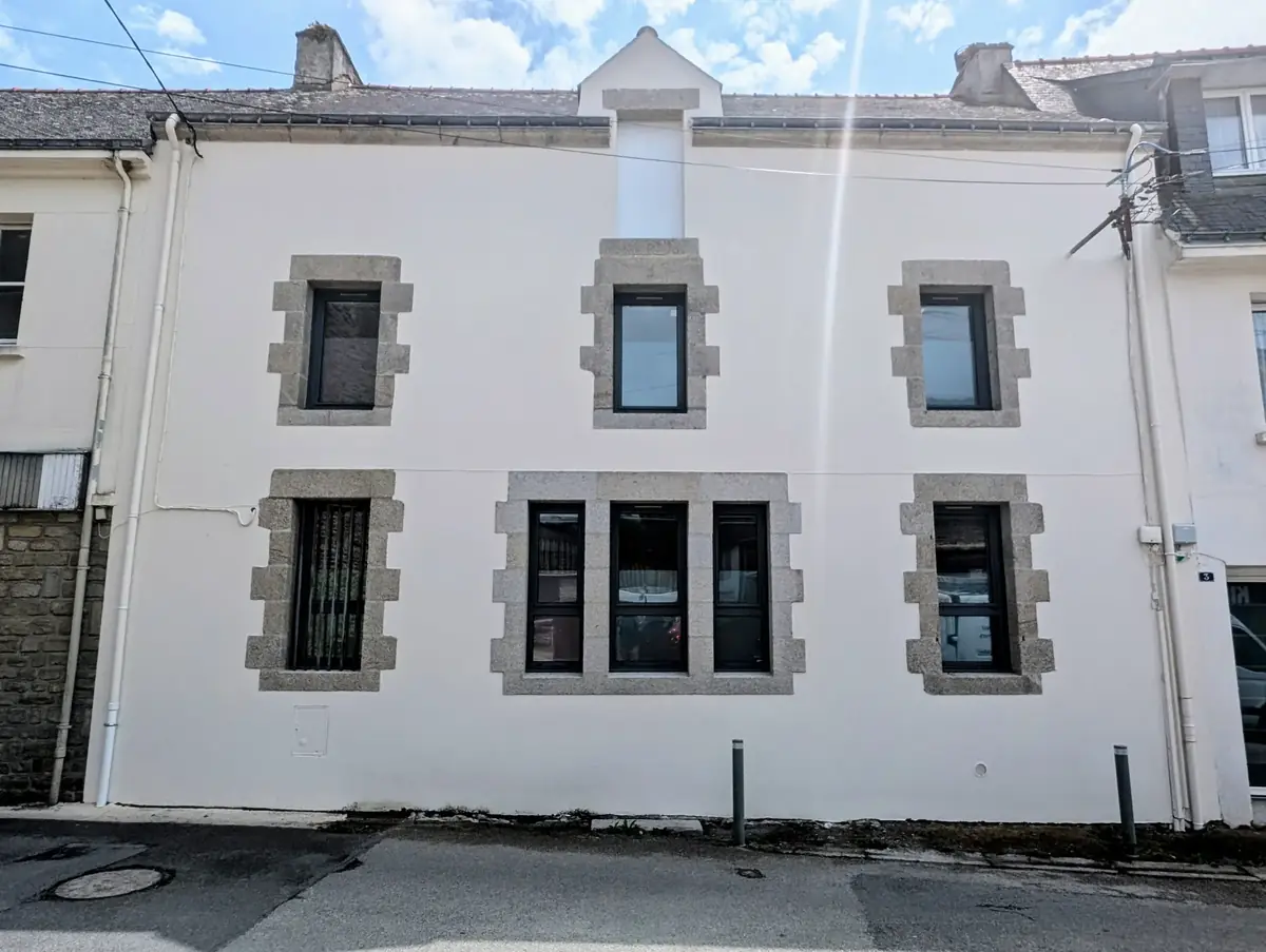Façade d’un immeuble de bourg de Sarzeau après ravalement, enduit clair et encadrements de granit apparents