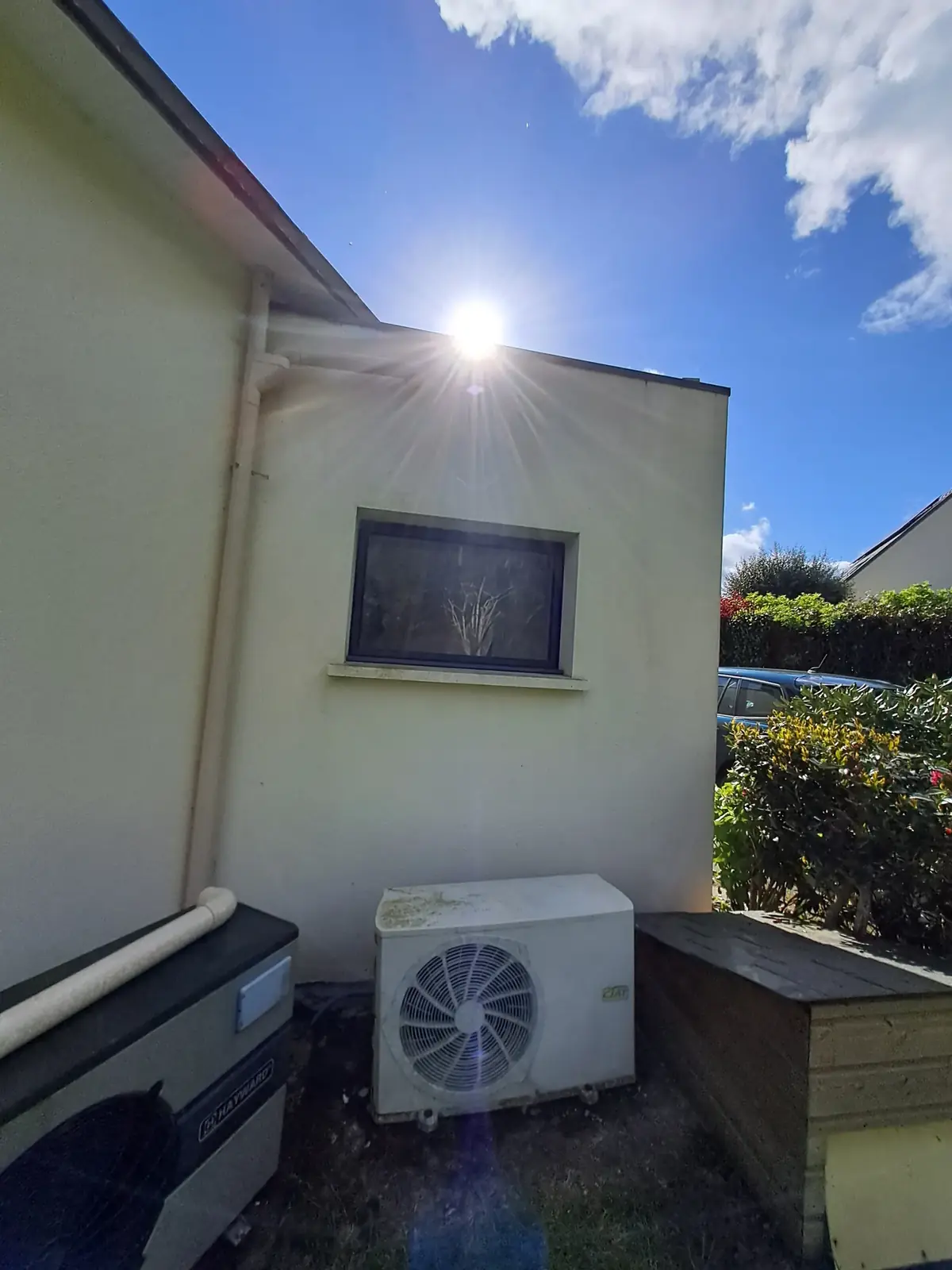 Pignon d’une maison de Tréffléan à contre-jour après mise en peinture, équipements techniques au pied du mur