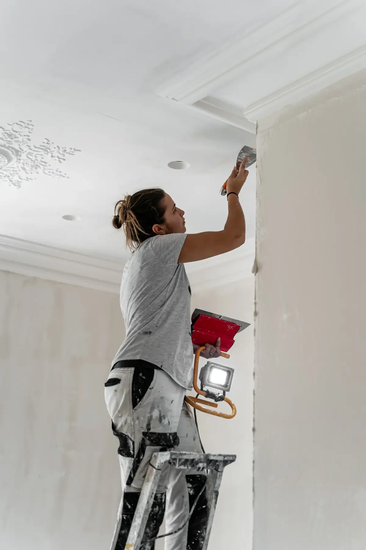 Compagnonne DEBAYS sur escabeau, reprise d’une corniche au plafond