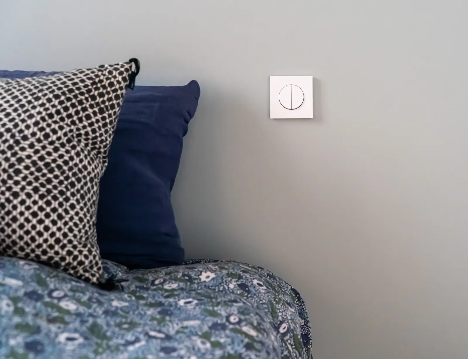 Chambre aux murs bleu gris, coussins et tête de lit