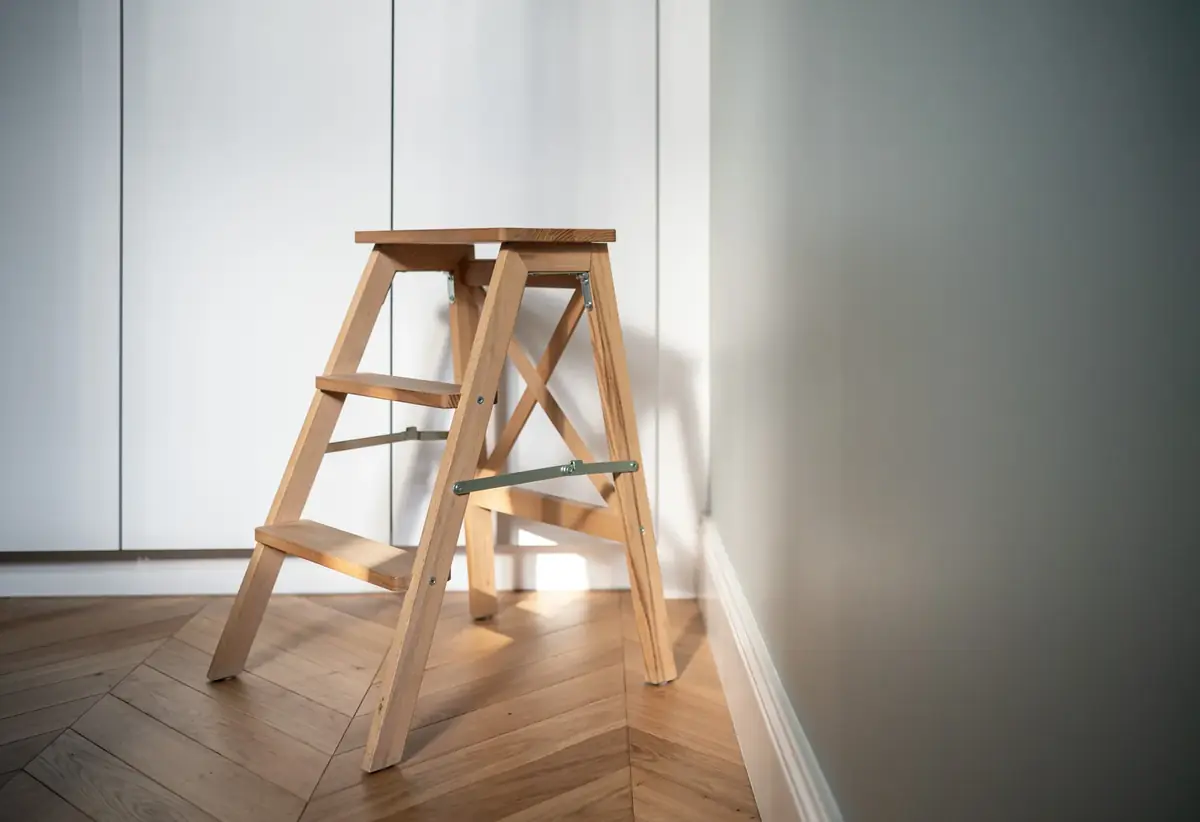 Escabeau en bois sur parquet en chevrons, mur vert de gris