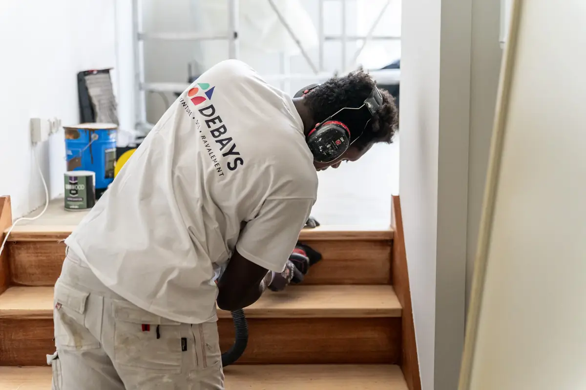 Compagnon DEBAYS ponçant les marches d’un escalier en bois