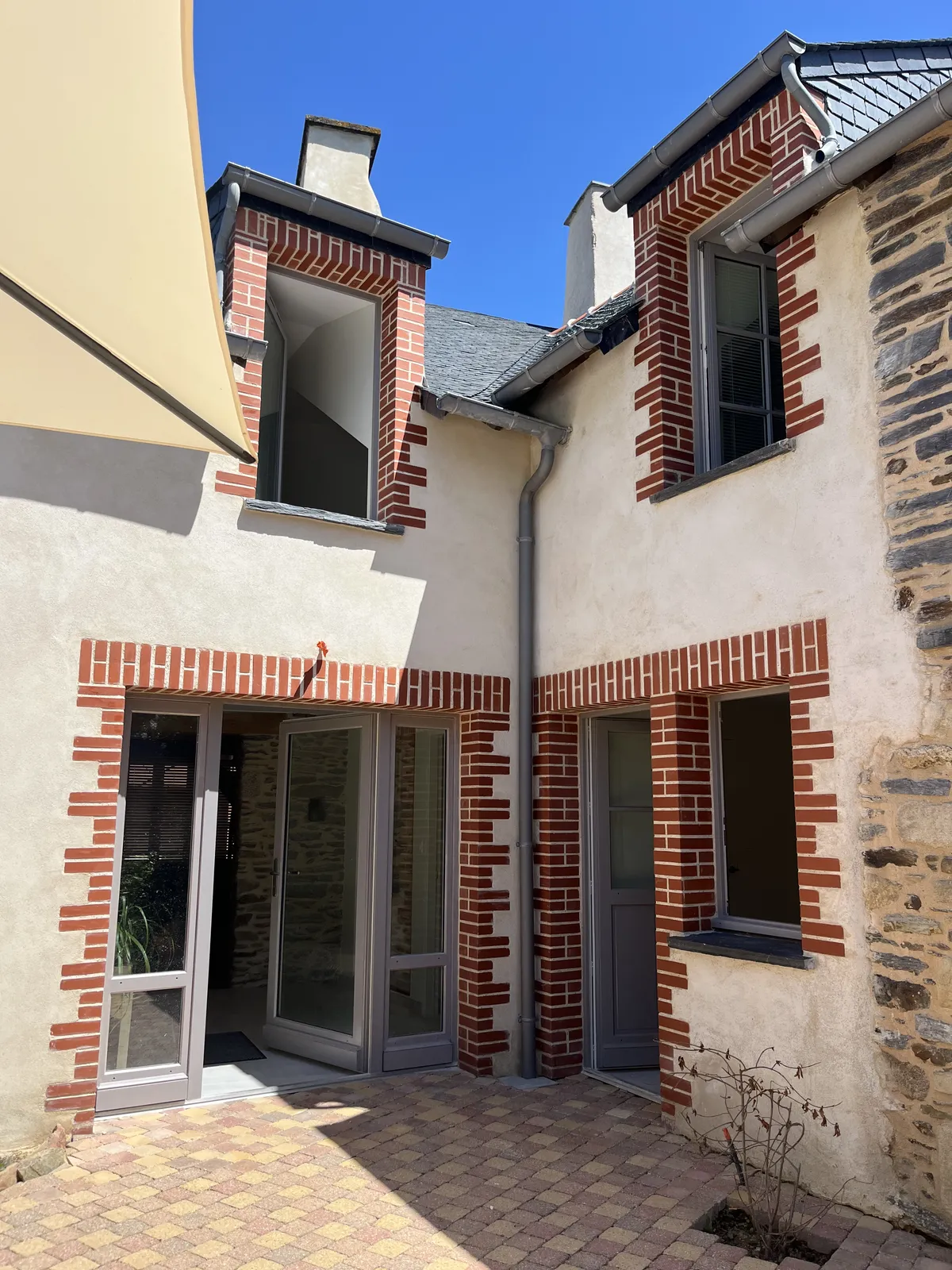 Façade de maison rénovée, encadrements en briques et enduit clair