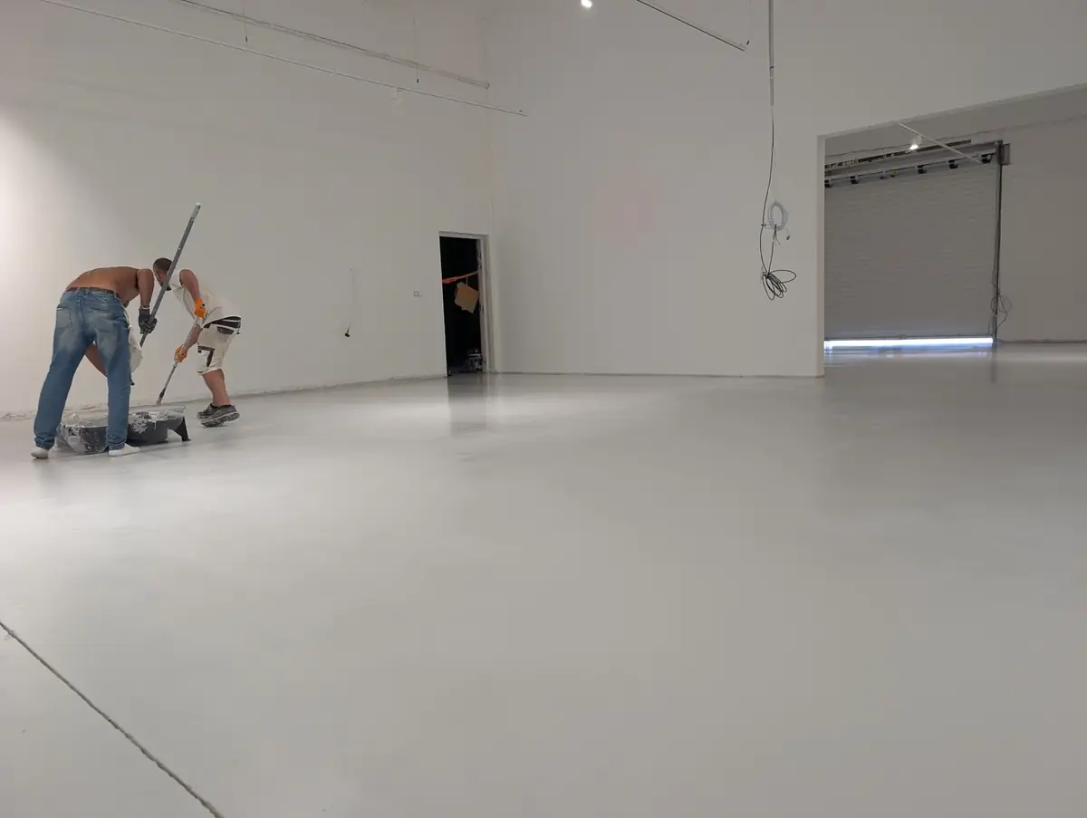 Compagnons appliquant la peinture de sol au rouleau dans un atelier