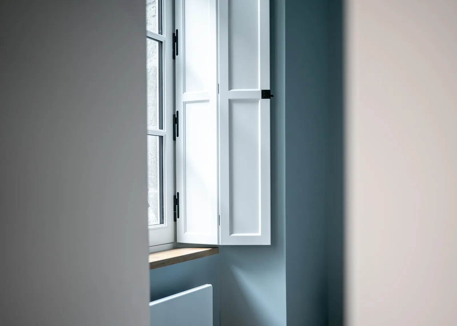 Fenêtre ancienne aux volets intérieurs, mur bleu gris