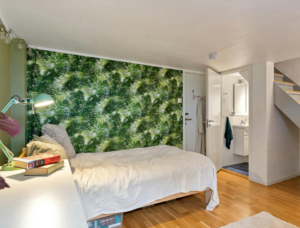 Lit blanc sur un parquet bois avec un mur coloré.