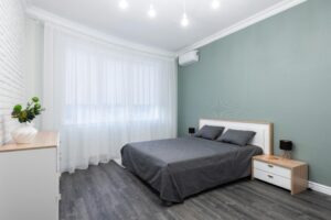 Chambre avec un lit gris foncé dans une chambre claire.